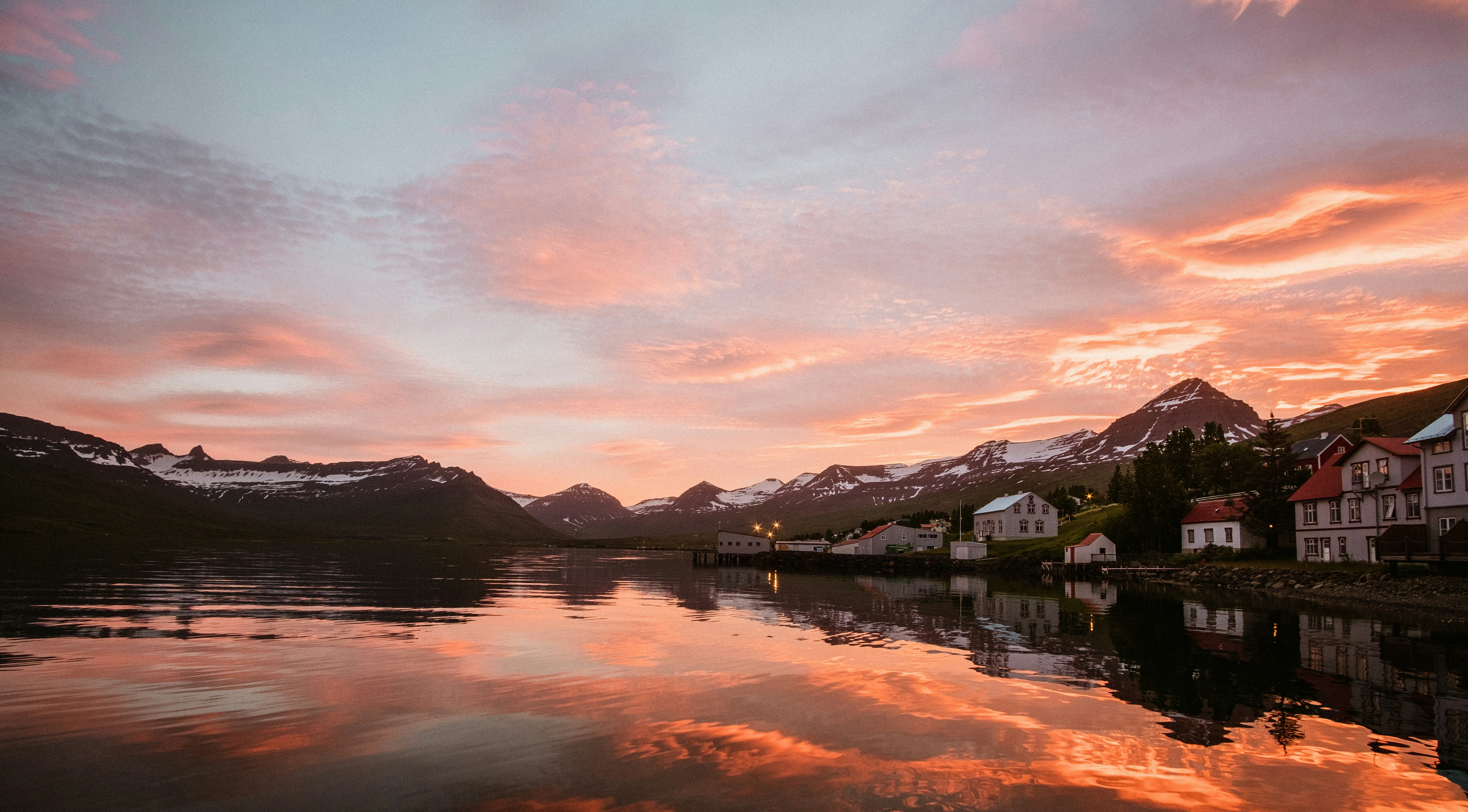Midnight sun reflecting pink and gold over an Icelandic village and water